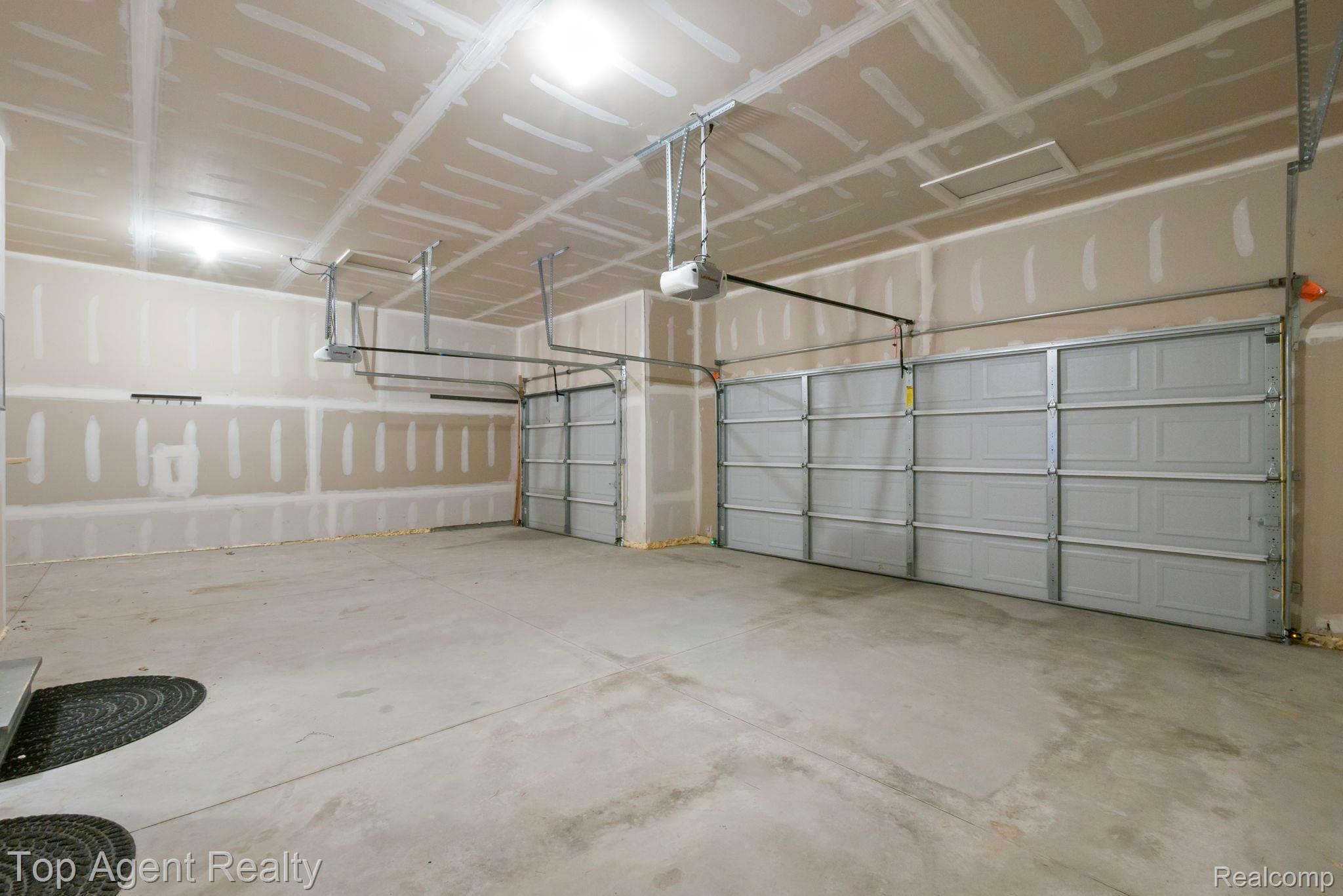 63770 Dequindre Road Washington, MI 48095 - Photo 51 of 61 Spacious garage featuring two sectional overhead doors with automatic openers, exposed drywall finishes, and a concrete floor