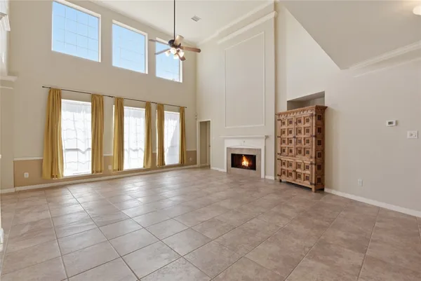 a view of an empty room with fireplace and windows