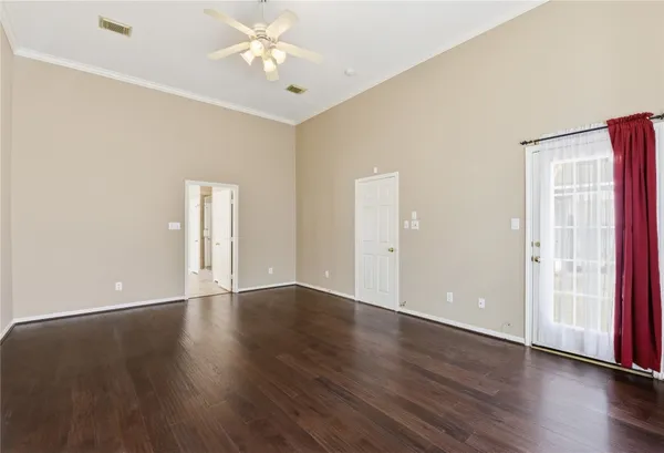 an empty room with wooden floor and ceiling fan
