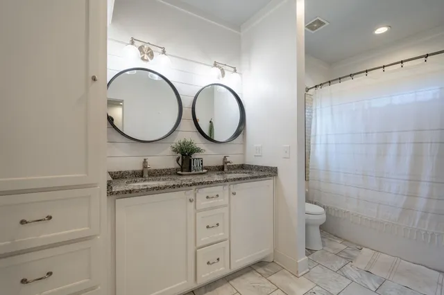 a bathroom with a granite countertop toilet a sink and a mirror