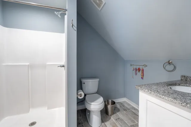 a bathroom with a granite countertop sink a toilet and shower