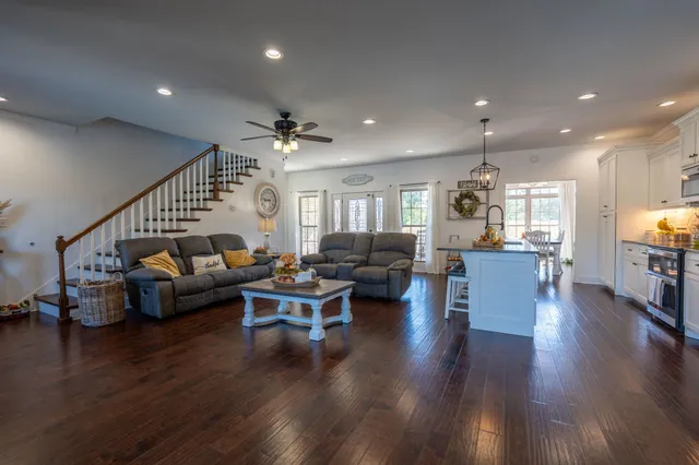 a living room with furniture wooden floor and a kitchen view