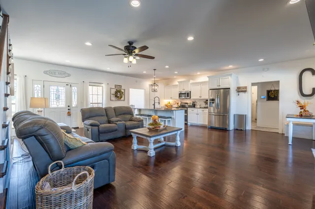 a living room with furniture and kitchen view with wooden floor