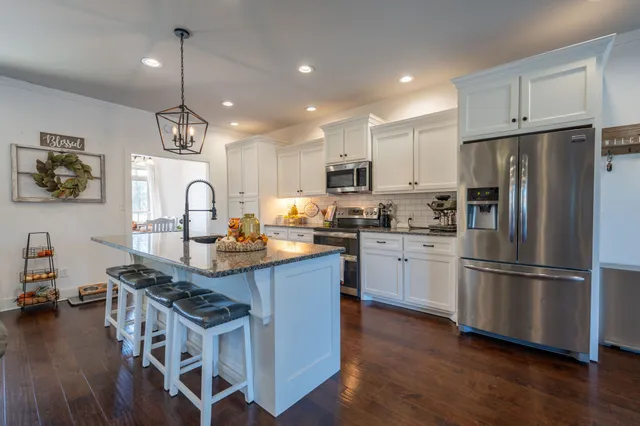 a kitchen with kitchen island stainless steel appliances a sink a stove a refrigerator and wooden floor