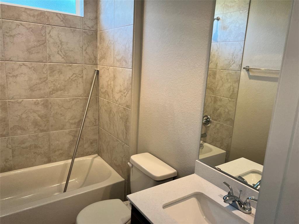 128 Free Stone Drive Georgetown, TX 78628 - Photo 9 of 29 Bathroom with a tiled bath/shower combination, a vanity with an integrated sink, a large mirror, and a toilet