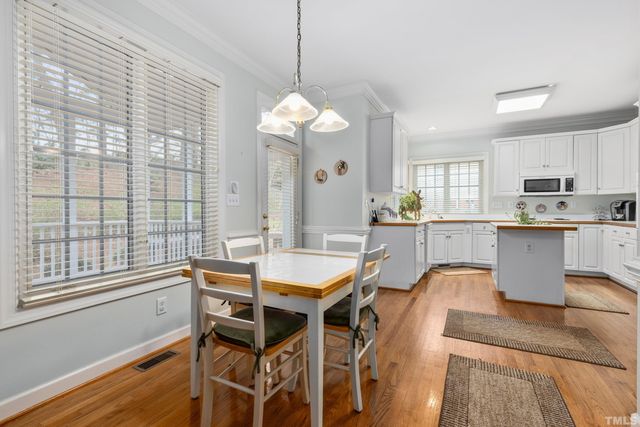 a dining room with wooden floor a chandelier a wooden table and chairs