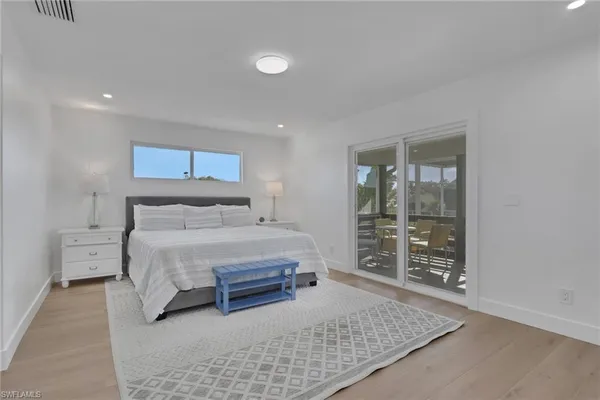 a bedroom with a bed and a walk in closet with wooden floor