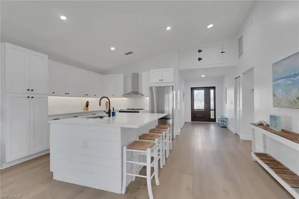 a large kitchen with stainless steel appliances lots of white furniture