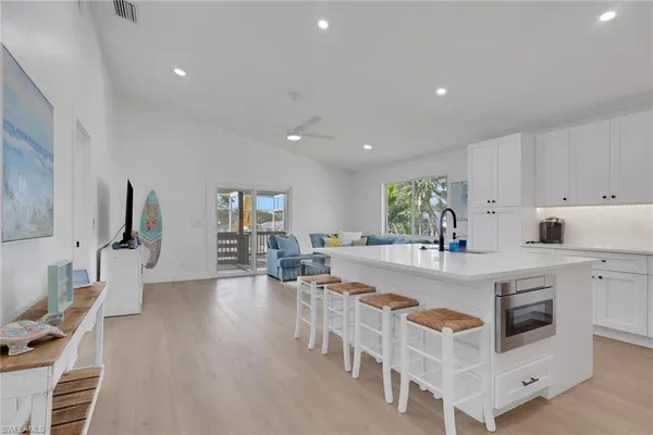 a large white kitchen with wooden floor and stainless steel appliances