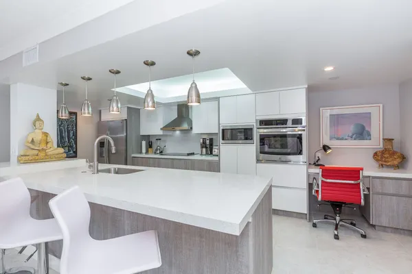 a kitchen with stainless steel appliances kitchen island granite countertop a sink and a white cabinets