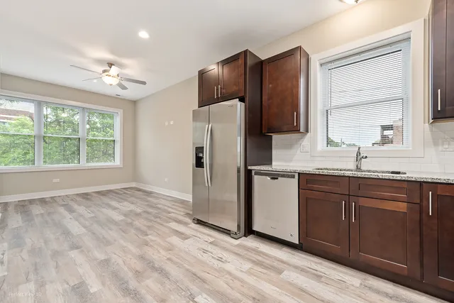 a kitchen with stainless steel appliances granite countertop a refrigerator sink and wooden cabinets