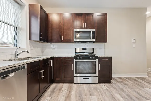 a kitchen with stainless steel appliances granite countertop a stove a sink and a microwave
