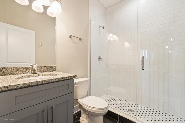 a bathroom with a granite countertop sink a toilet a mirror and shower