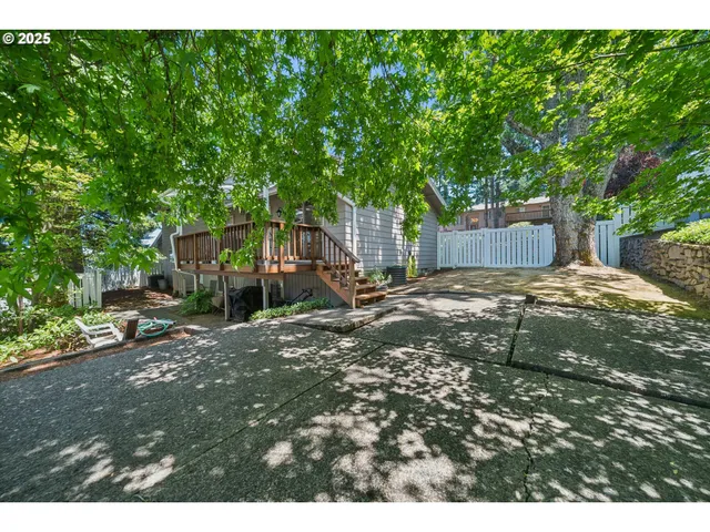 a view of a backyard with large trees and a barn