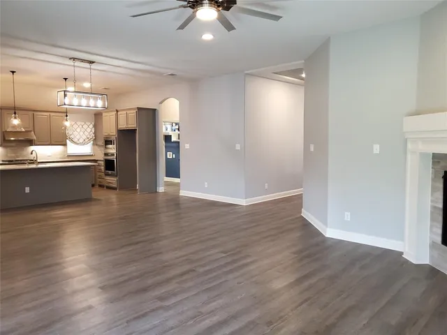 an empty room with wooden floor and a kitchen