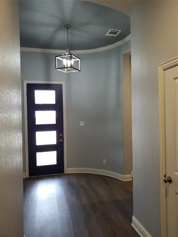an empty room with wooden floor exposed radiator and windows