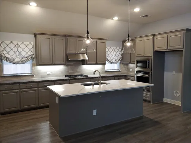 a kitchen with stainless steel appliances granite countertop a sink a stove and a refrigerator