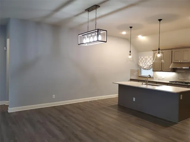 a view of a room with kitchen island stainless steel appliances wooden floor and a chandelier
