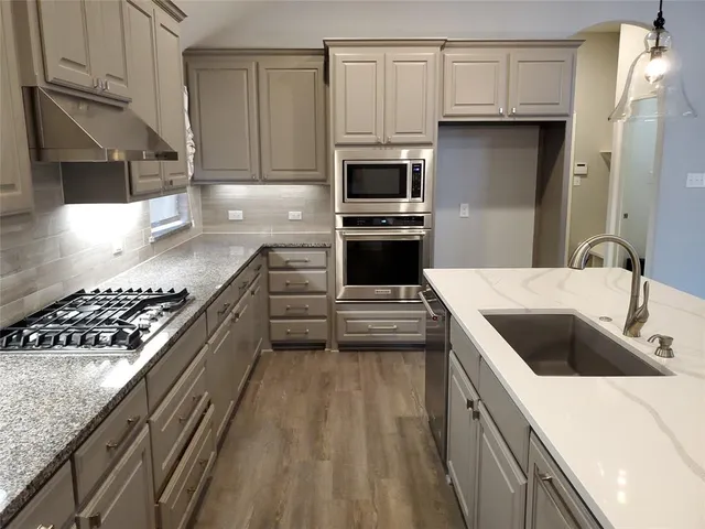 a kitchen with granite countertop a sink and steel appliances