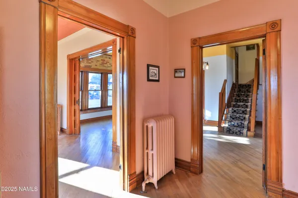a view of a hallway with wooden floor and living room