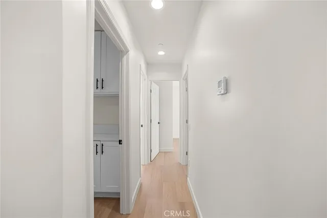 a view of a hallway with wooden floor and a bathroom