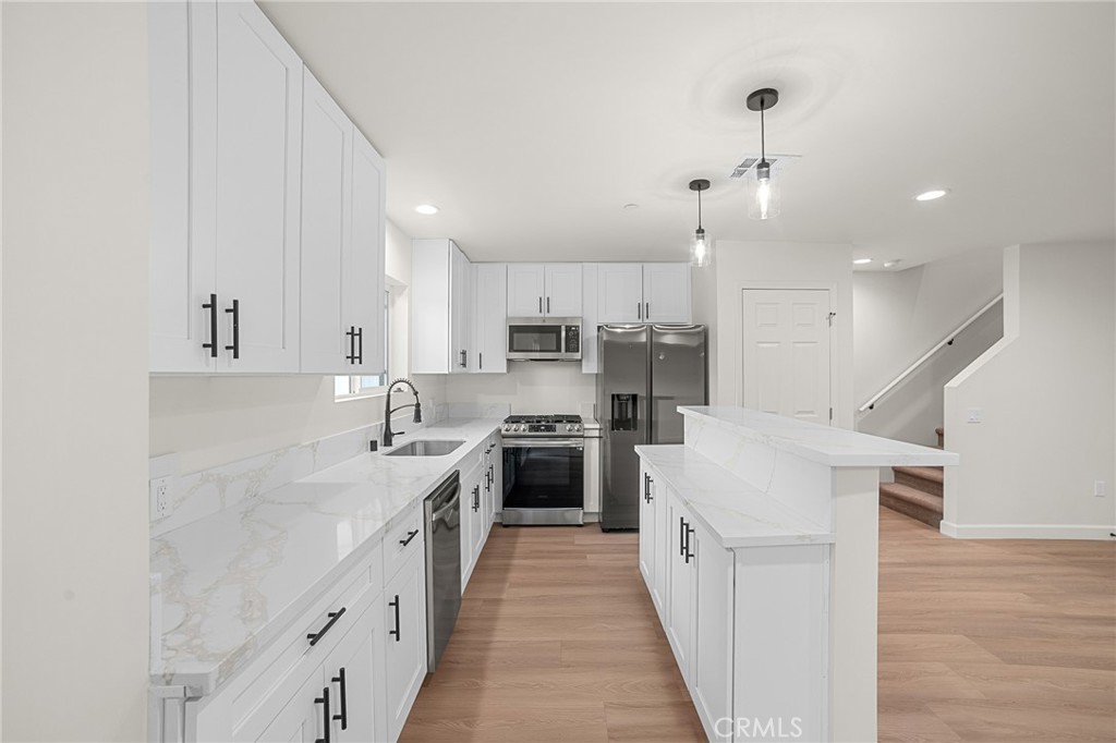 900 South Hert Street Colton, CA 92324 - Photo 6 of 26 a large kitchen with stainless steel appliances kitchen island granite countertop a stove a sink a refrigerator and white cabinets with wooden floor