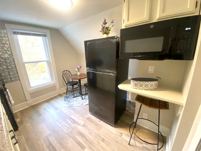 a kitchen with stainless steel appliances granite countertop a refrigerator a stove a microwave oven with white cabinets and wooden floor