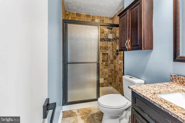 a bathroom with a granite countertop toilet a sink and a mirror