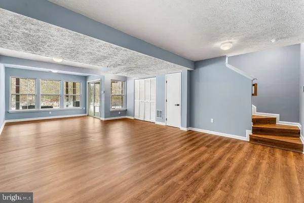 a view of an empty room with window and wooden floor