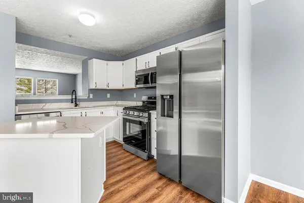 a kitchen with stainless steel appliances granite countertop a refrigerator a sink and a stove