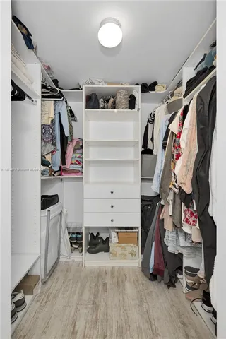 a view of walk in closet with clothes and shoes