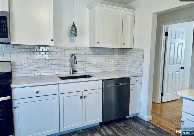 a kitchen with white cabinets and sink