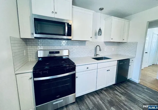 a kitchen with stainless steel appliances granite countertop white cabinets stove top oven and sink