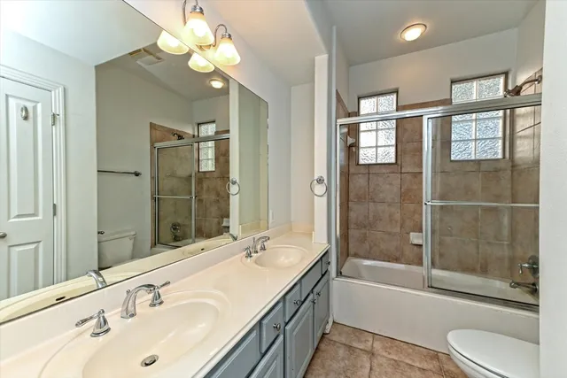 a bathroom with a granite countertop sink a toilet and shower