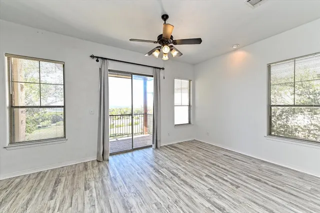 a view of an empty room with a window and wooden floor