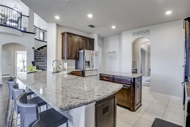 a kitchen with kitchen island granite countertop a table chairs sink and refrigerator