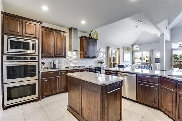 a kitchen with stainless steel appliances granite countertop a sink and a refrigerator