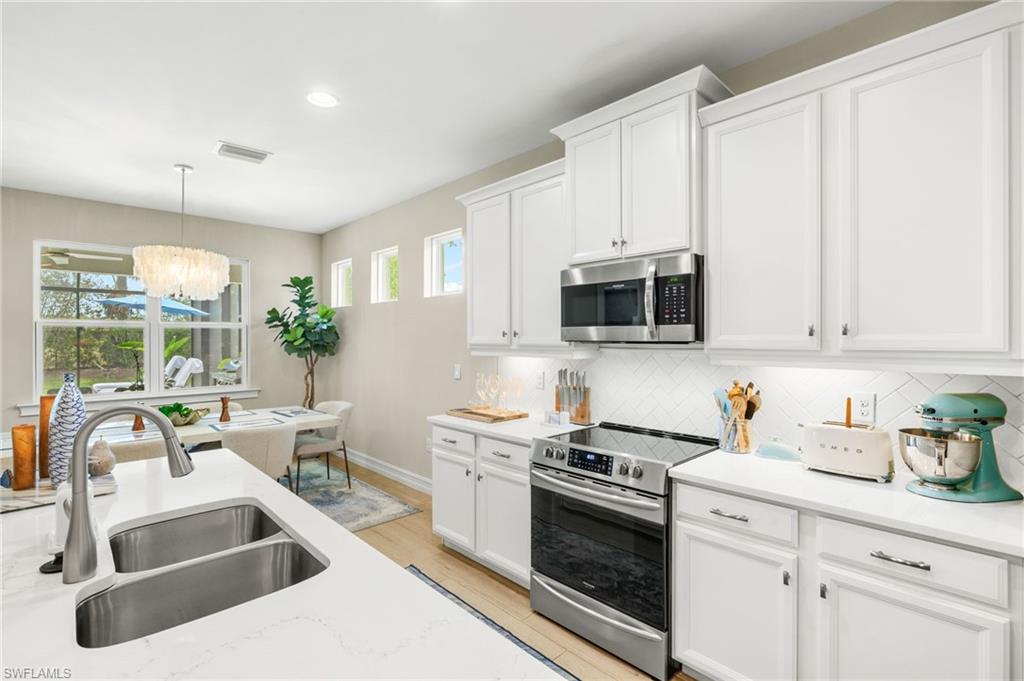 14546 Tropical Drive Naples, FL 34114 - Photo 12 of 38 a kitchen with stainless steel appliances a white stove top oven and white cabinets