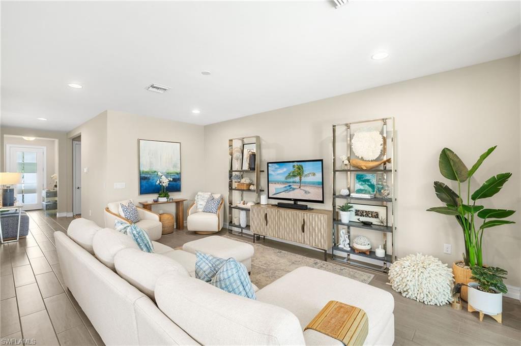 14546 Tropical Drive Naples, FL 34114 - Photo 2 of 38 a living room with furniture a potted plant and a flat screen tv