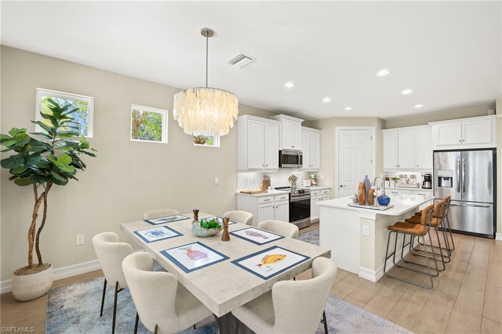14546 Tropical Drive Naples, FL 34114 - Photo 7 of 38 a view of a dining room and livingroom with furniture wooden floor a rug a potted plant and a chandelier