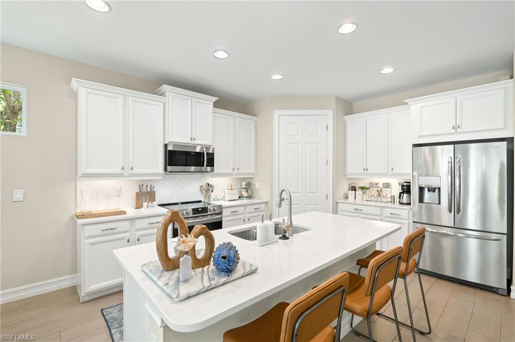 14546 Tropical Drive Naples, FL 34114 - Photo 8 of 38 a kitchen with stainless steel appliances granite countertop a dining table chairs refrigerator and sink