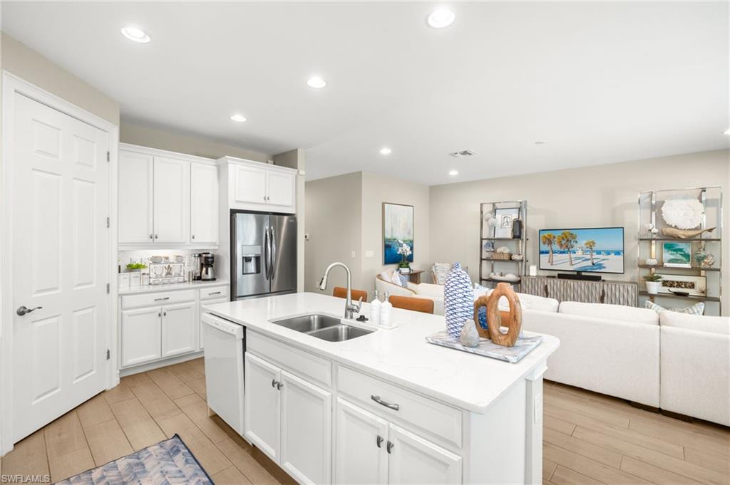 14546 Tropical Drive Naples, FL 34114 - Photo 9 of 38 a kitchen with white cabinets and stainless steel appliances