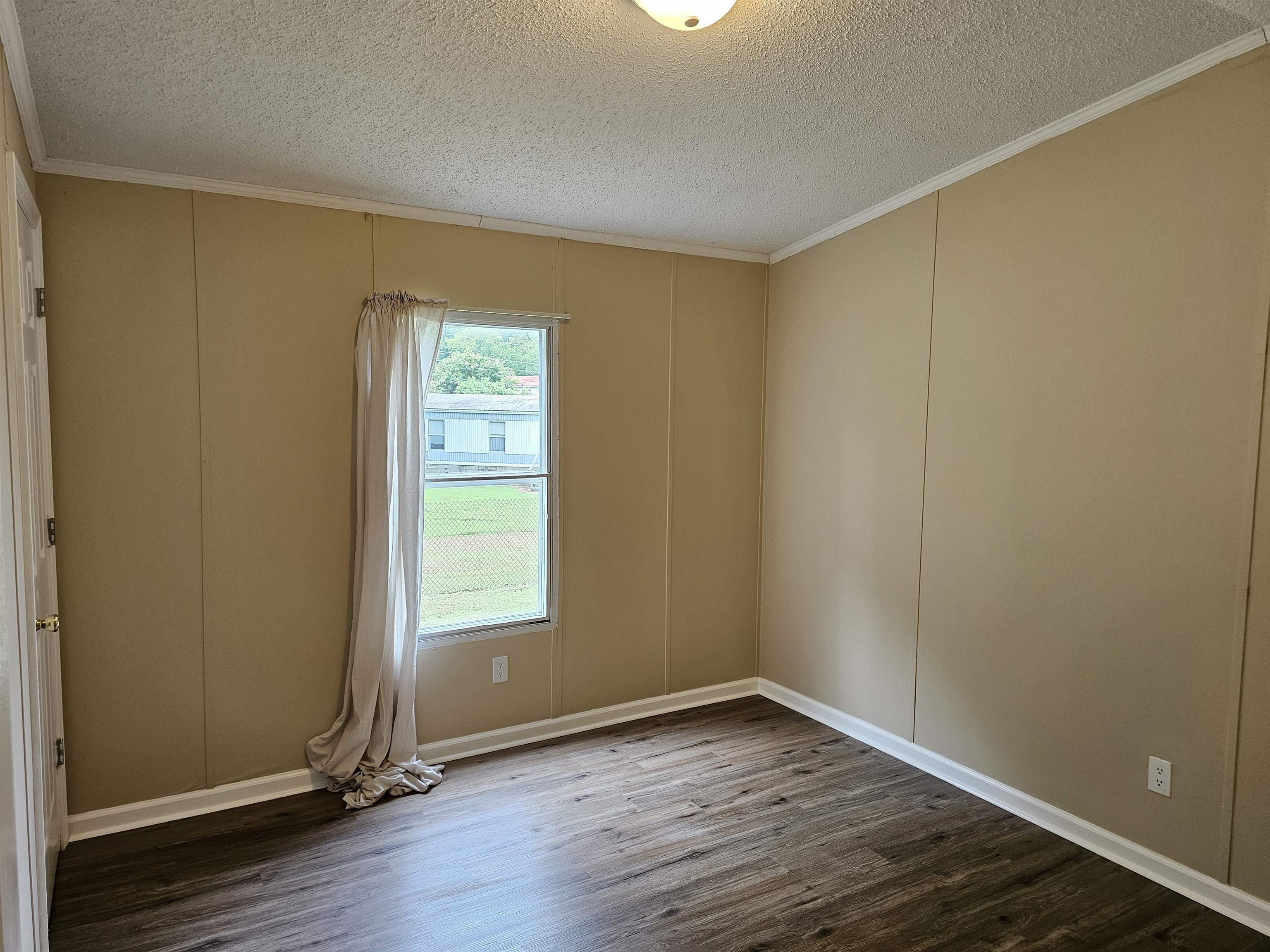 474 Fite Road Munford, TN 38058 - Photo 13 of 19 Empty room with wood finished floors, a decorative wall, ornamental molding, and a textured ceiling