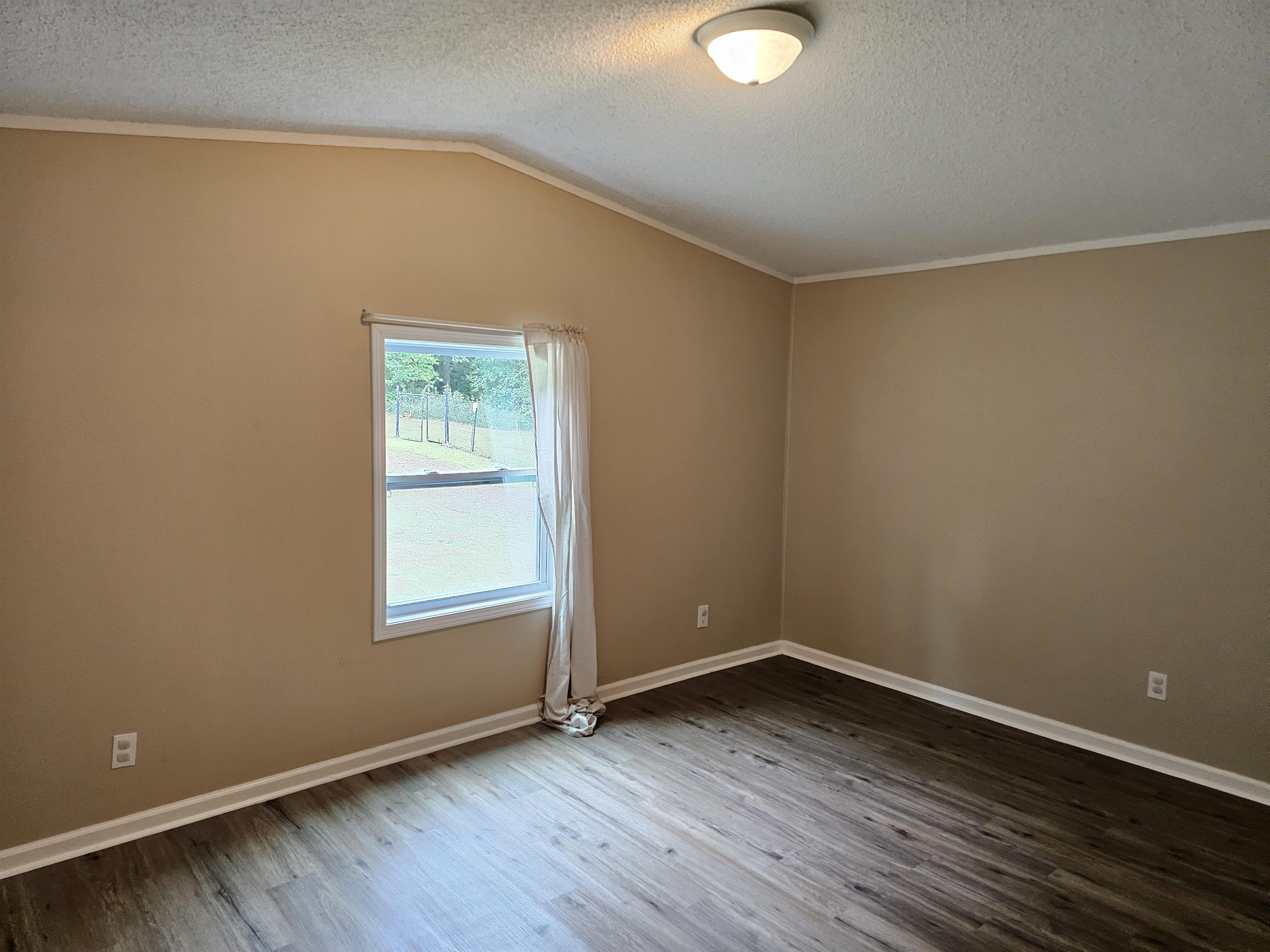 474 Fite Road Munford, TN 38058 - Photo 15 of 19 Spare room featuring crown molding, dark wood-type flooring, lofted ceiling, and a textured ceiling