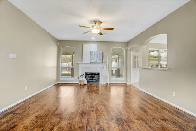 an empty room with wooden floor fireplace and windows