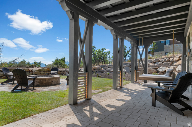 2192 East Outlaw Road Kamas, UT 84036 - Photo 20 of 80 Expansive outdoor living area featuring a paved patio, a built-in fire pit, a covered pergola, and a stone retaining wall
