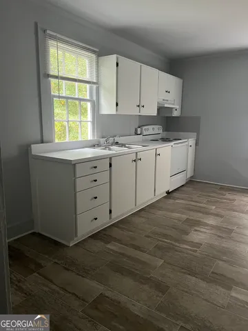 a kitchen with granite countertop white cabinets and a window