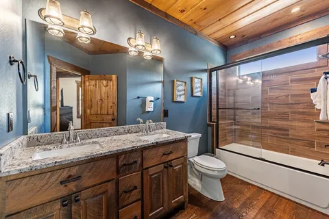 a bathroom with a granite countertop sink a toilet a mirror and shower