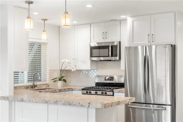 a kitchen with stainless steel appliances granite countertop a refrigerator a stove a sink and a granite counter tops