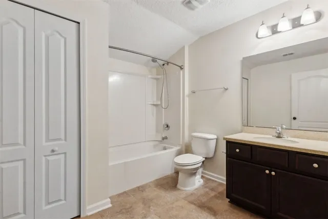 a spacious bathroom with a double vanity sink toilet mirror and shower